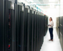 A woman standing in a data center amid rows of server racks