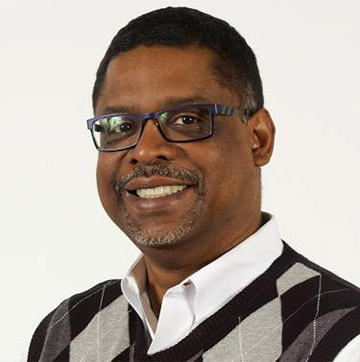 DePriest Dockins wears a collared shirt and argyle sweater.